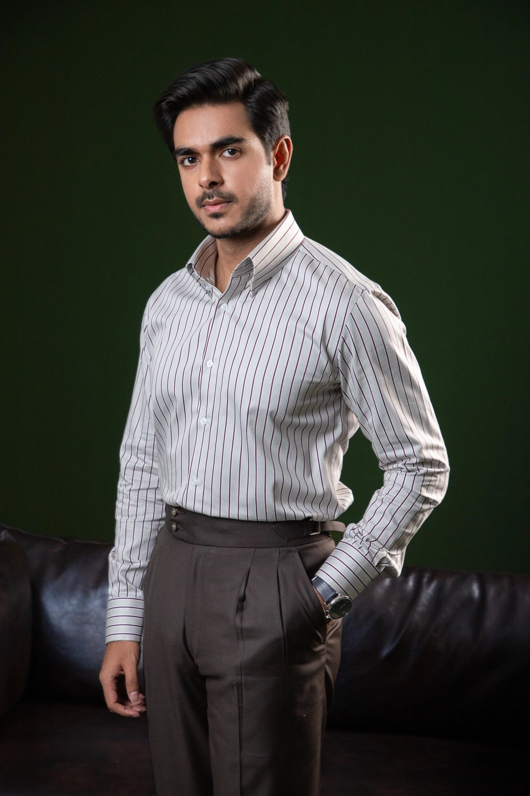 Man wearing a striped shirt and dark pants against a dark background